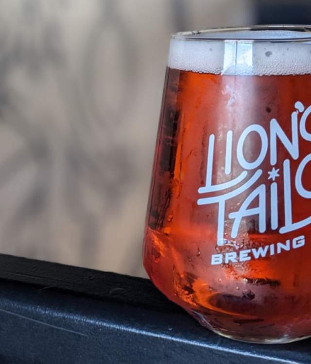 Glass of amber beer bearing the Lion’s Tail Brewing Co. logo.