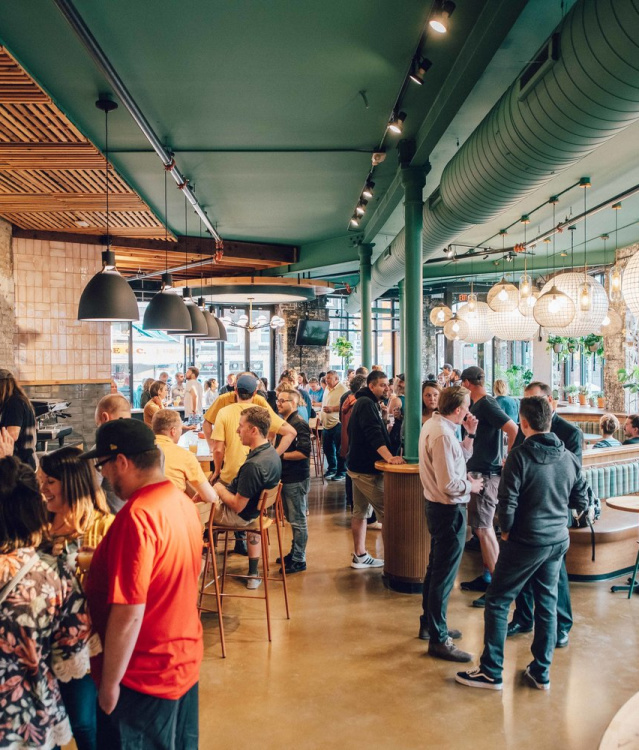 A group of diners talking and eating inside of the Triple Taproom & Kitchen on Milwaukee's East Side