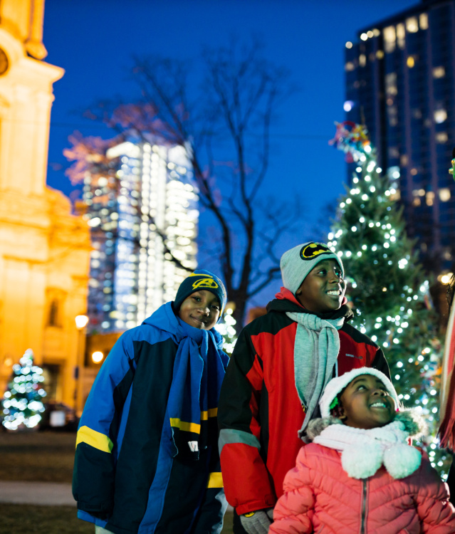 a family of four smiling during Milwaukee's Holiday Lights festival in Cathedral Square