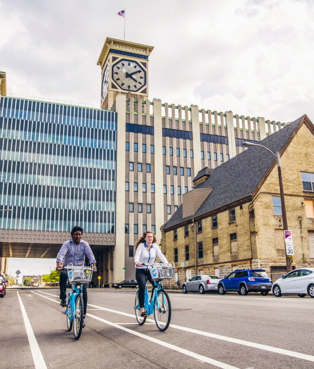 two people using bublr bikes, biking under the clocktower