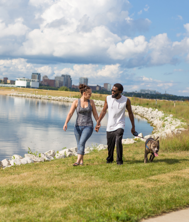 Couple waling a dog along the shores of Lakeshore State Park