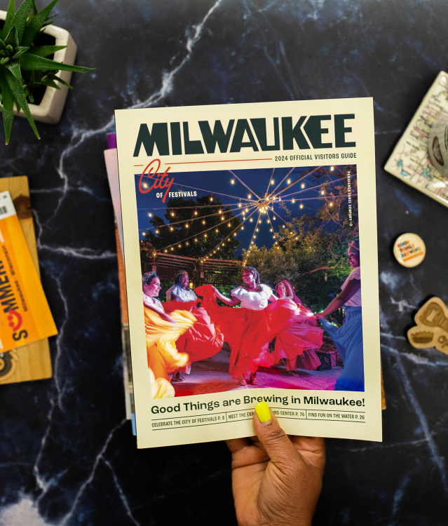 layflat of Milwaukee visitors guide held up over an array of milwaukee items