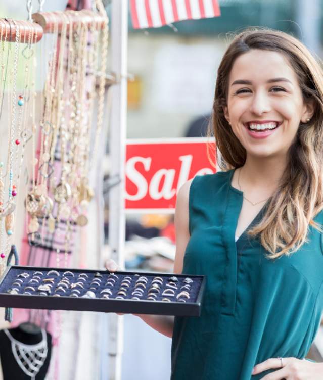 Jewelery vendor showing rings and smiling