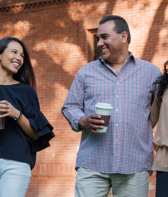 A family holding coffee cups smiling on the University of Oklahoma Campus in Norman, Oklahoma.