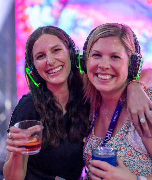 Two women wearing headphones at an event.