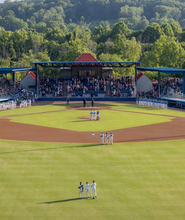 Players and fans standing for national anthem at baseball game