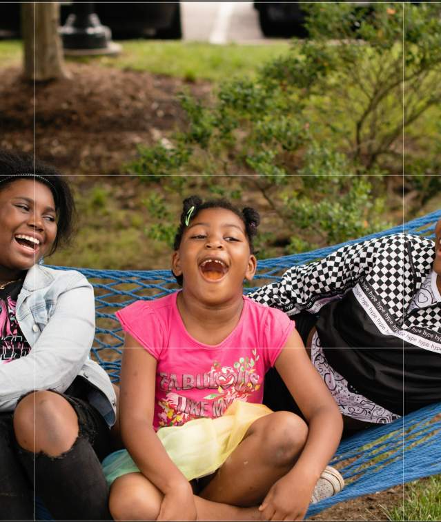 three girls swinging and laughing in a hammock