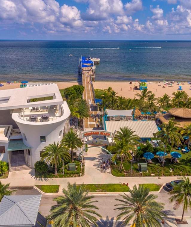 An aerial view of Oceanic, the Fisher Family Pier and Lucky Fish at Pompano Beach, FL on a beautifully sunny day.