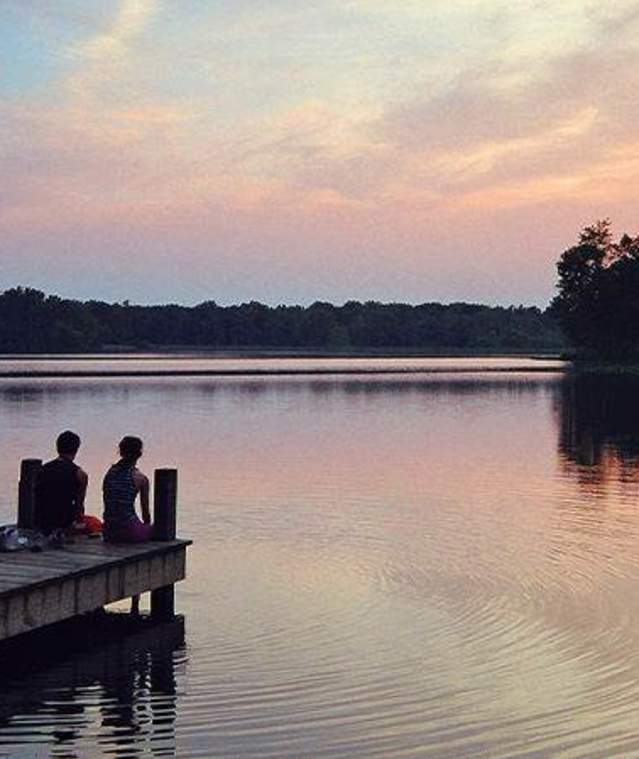 Couple sitting on a dock at sunset