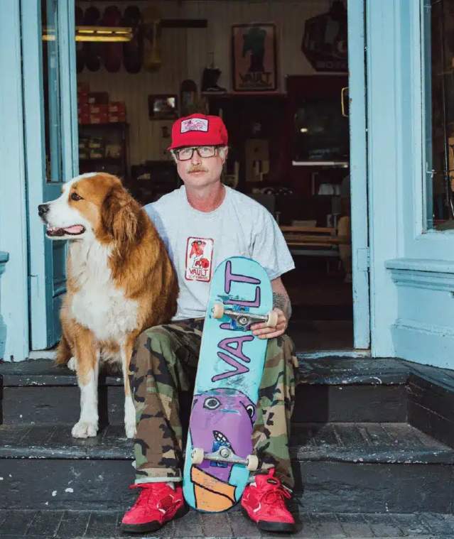 man sitting with a dog and a skateboard