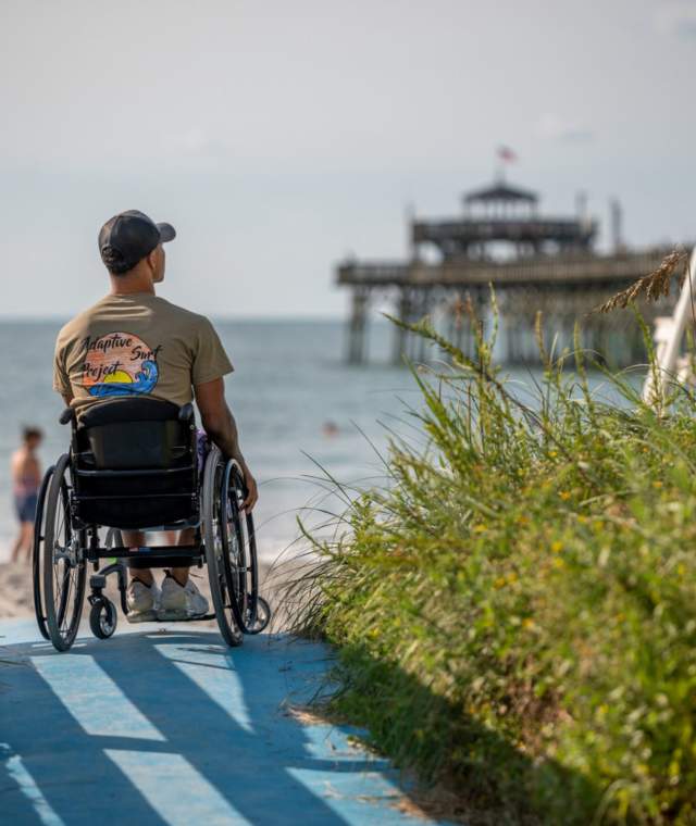 a man in a wheelchair looking at the Cherry Grove Pier