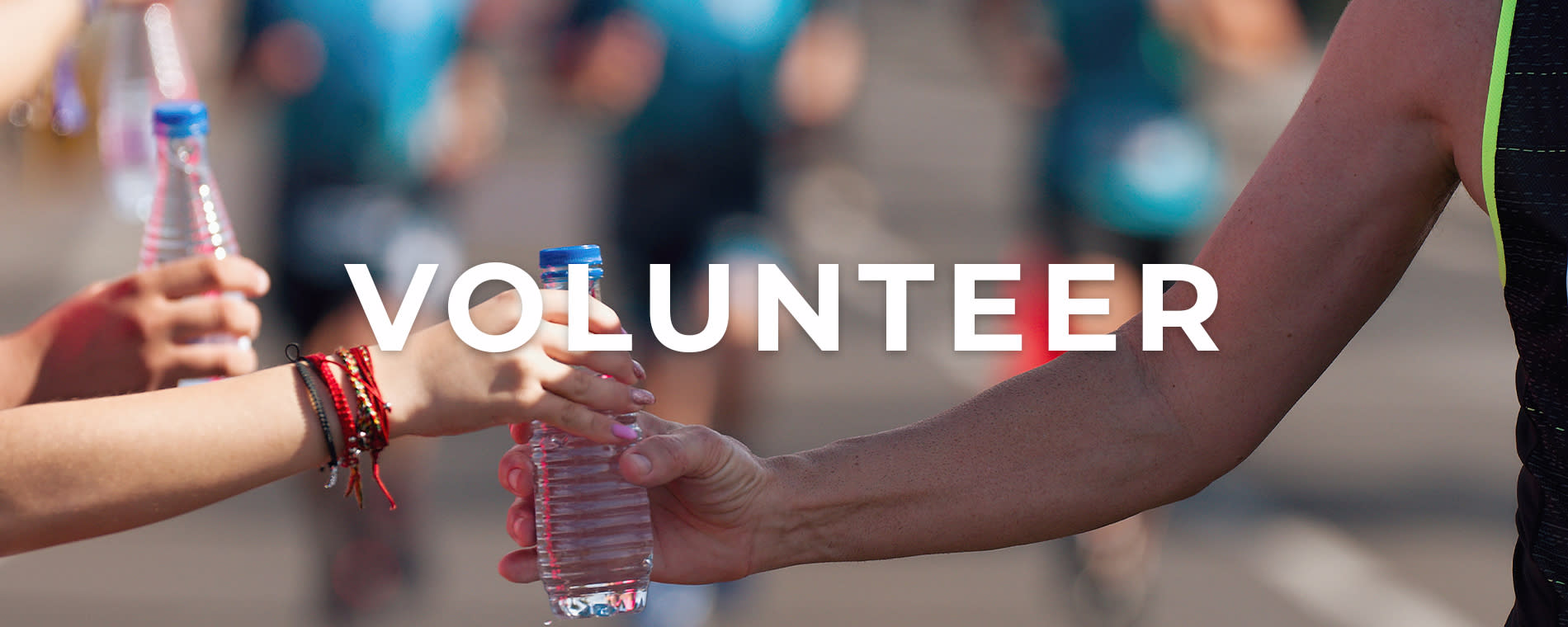 One person hands a water bottle to another with white "Volunteer" text over the image