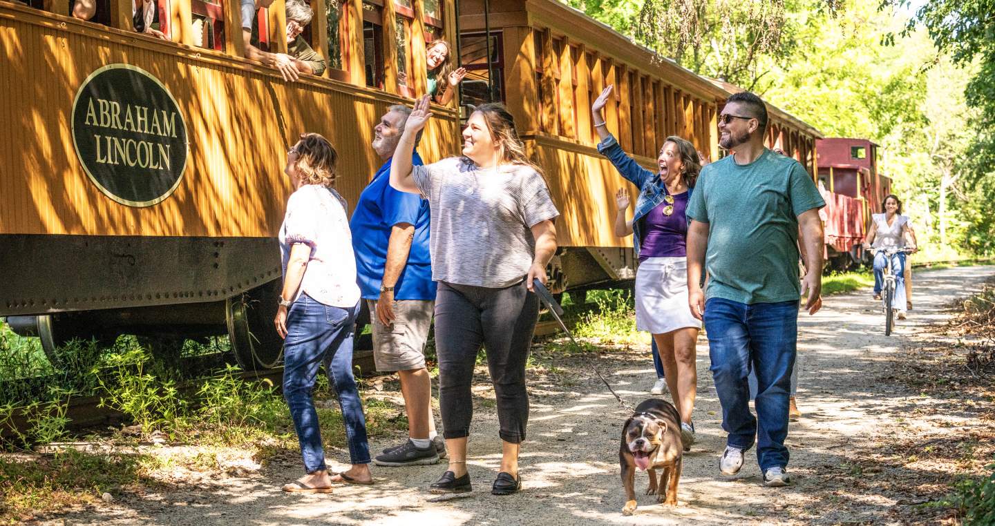 People enjoying a beautiful day walking alongside the steam engine on the heritage rail trail