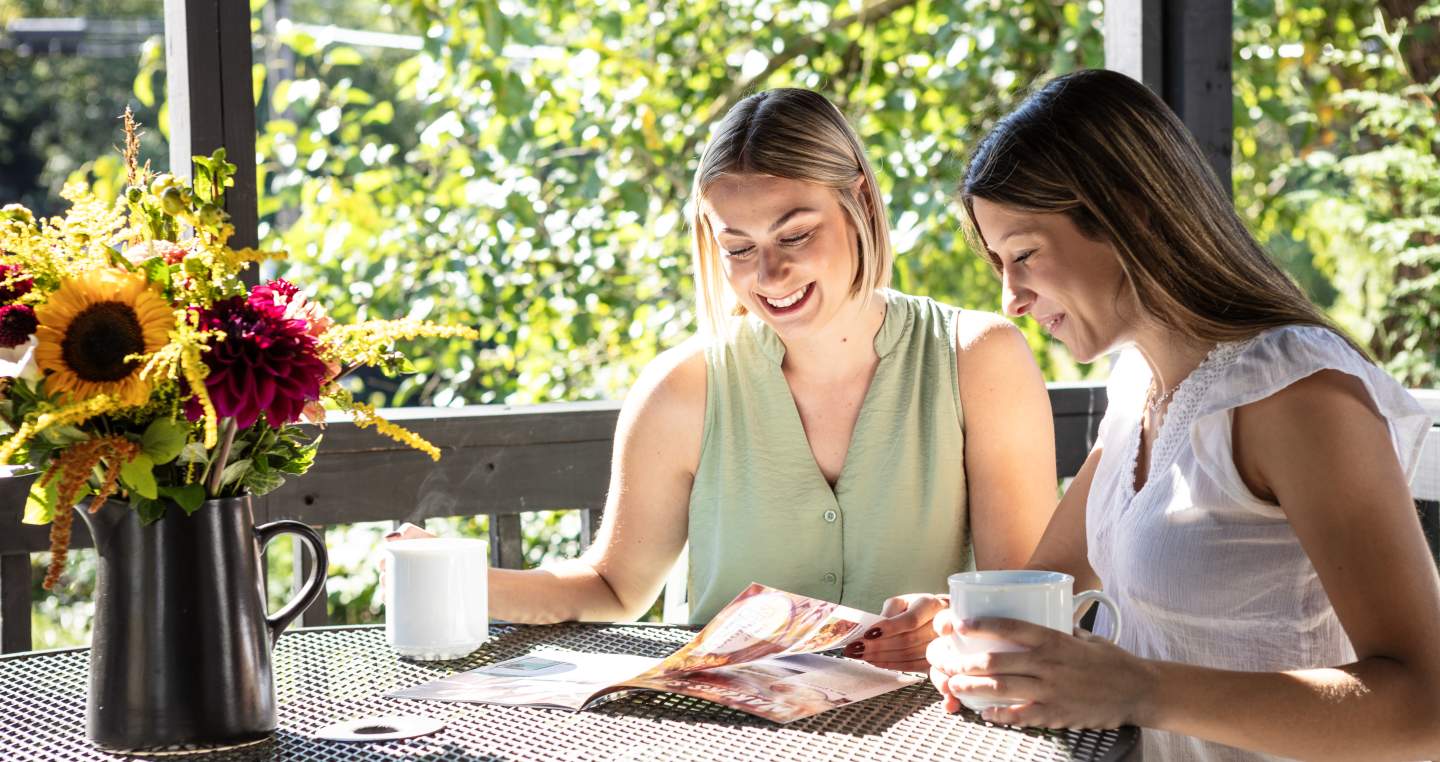 two women sitting at a table drinking coffee and planning their day using our York County Travel Guide