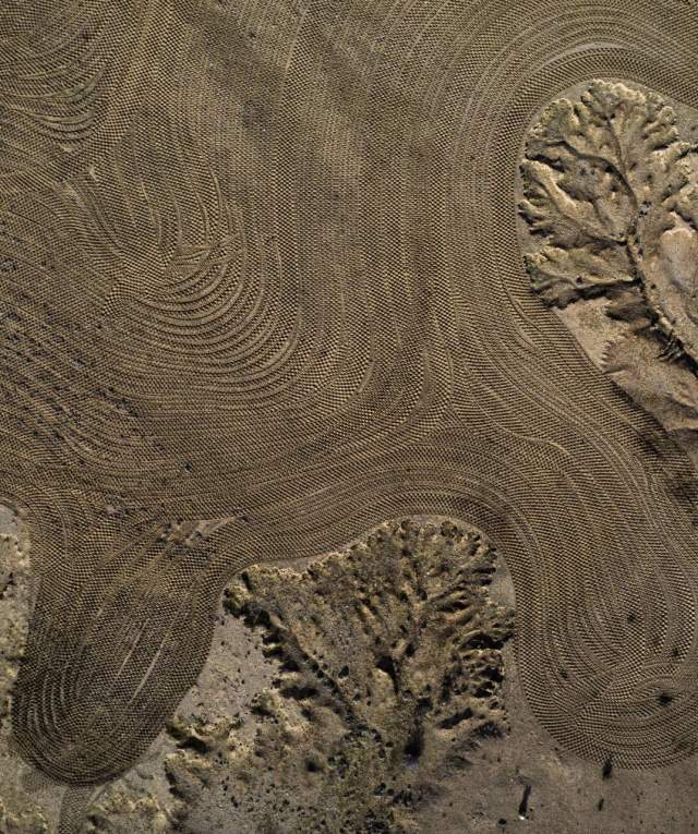 An aerial shot of a desert landscape showing unique formations in rock and sand