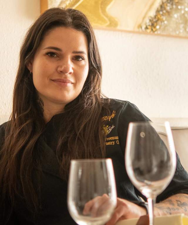 A person sits on a bench seat against a wall with two wine glasses in the foreground