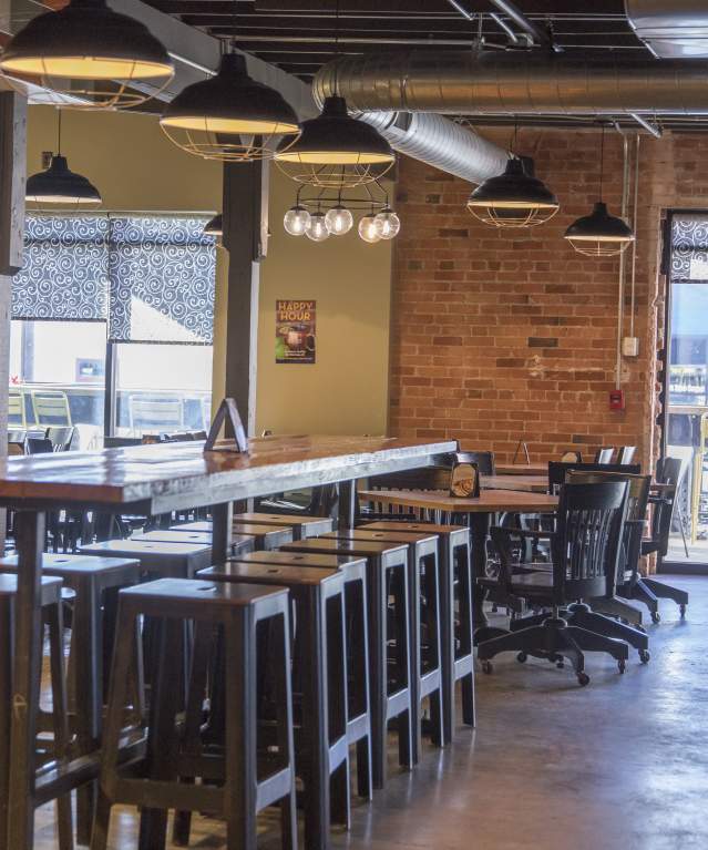 The inside of a restaurant with tabletop and booth seating, with access to outdoor seating.