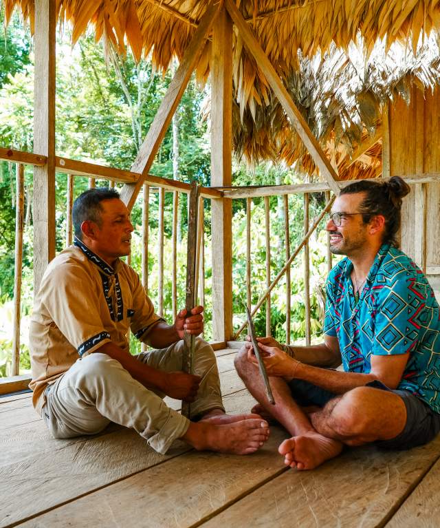 Naso Tjër Di man Interacting with a tourist inside a rural house in the community.