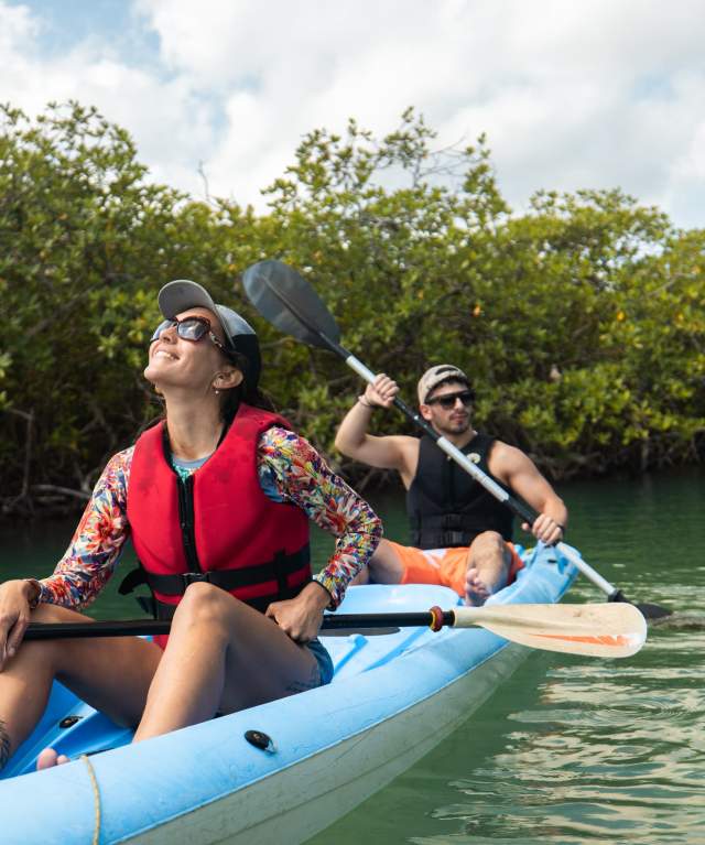 Couple kayaking on a river surrounded by mangroves during an ecotourism experience