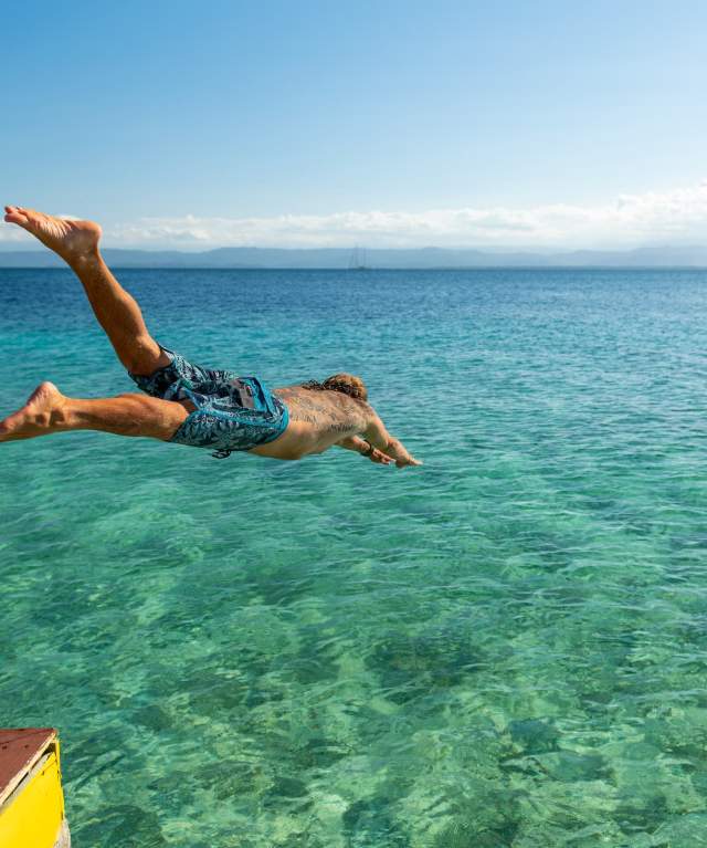 Man diving into the sea in crystal-clear waters of the Caribbean in Panama
