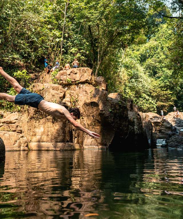 One person dives into the river with open arms, while another relaxes on a rock in Penonome