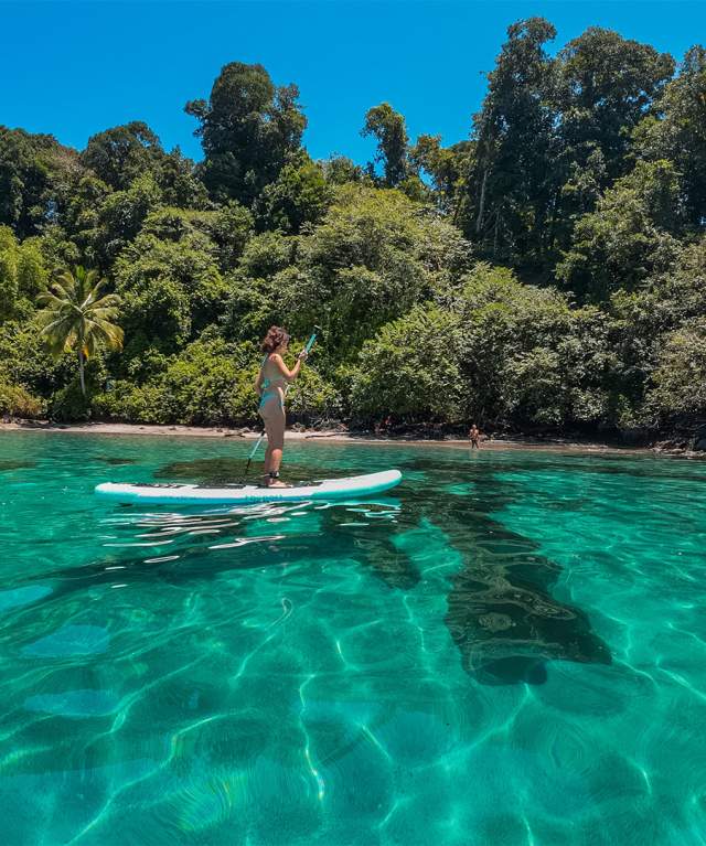 Woman doing paddle on a blue crystalline waters of Isla Cocos at Veraguas