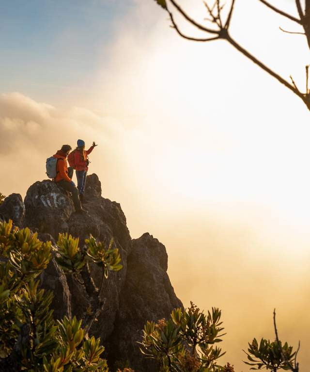 Atop Volcán Barú at sunset, a couple enjoys a panoramic vista overlooking a sea of clouds. This vantage point offers views of both the Pacific and Atlantic Oceans on clear days.