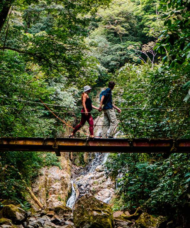 Couple walking on a hanging bridge at Sendero el Chorro