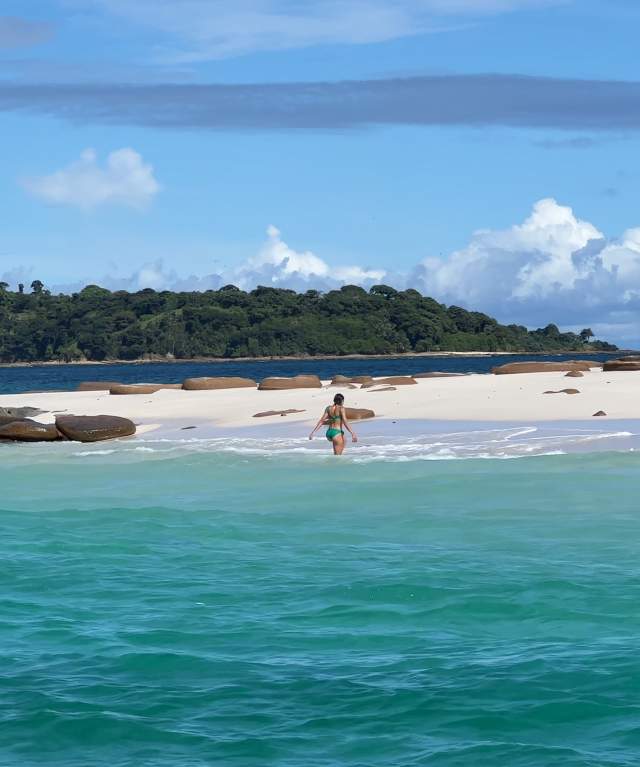 Woman walking along the beautiful sunny beach of Bartolome Island, Pearl Islands Panama City, Panamá