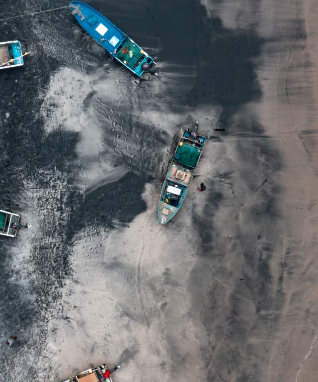 View of black sand of Gorgona beach, fishing boats