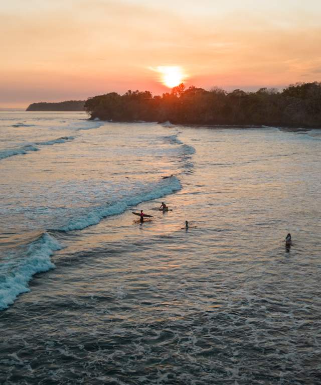 Aerial view of surfers riding the waves of Santa Catalina at sunset in Veraguas Province, Panama.