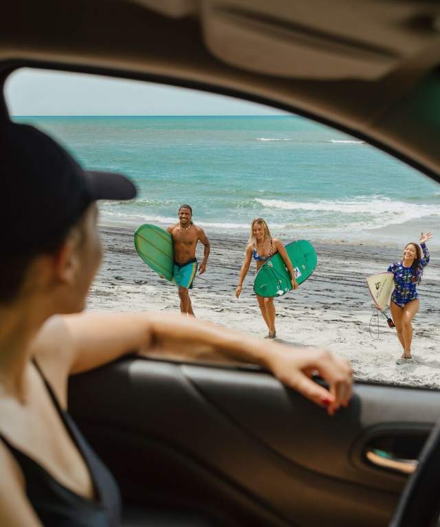 Surfer tourists walking along the beach carrying their surfboards in West Panama Province.