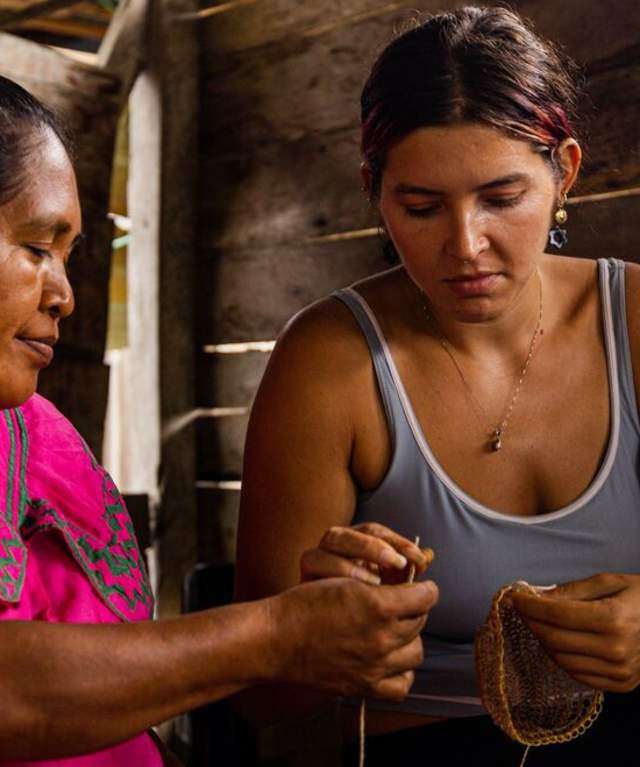 Ngäbe woman wearing  Nagua (traditional dress) hows visitor the weaving of a craft.