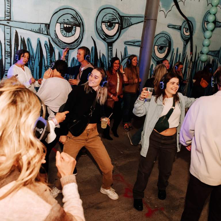 People partying in an alleyway in front of public art in Fort Wayne.