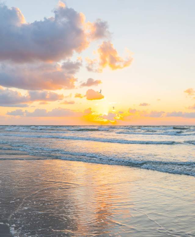 A bright, golden sunrise over the ocean waves on a beach in Port Aransas.