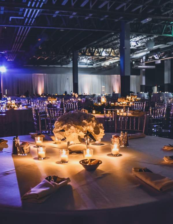 Ballroom set up with tables and candles and a band setting up