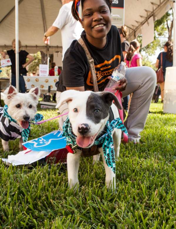 Women kneeling on grass posing with puppies at Dogtober Fest