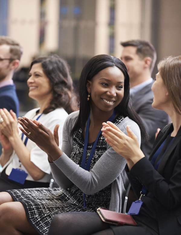 Attendees sitting in a meeting clapping