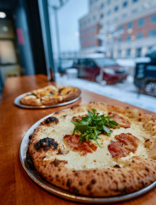 Two pizzas on a table by the window