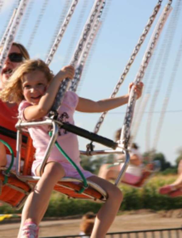 girl and mom on big swing ride at fairgrounds