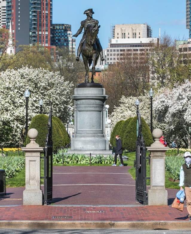 Masked parent and child holding hands in front of public garden