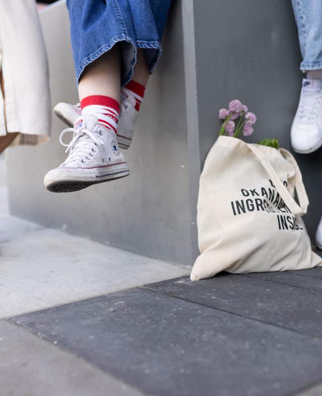 Close_Up_of_Feet_Dangling_from_Ledge_with_Tote_Bag_of_Market_Flowers_and_Local_Produce