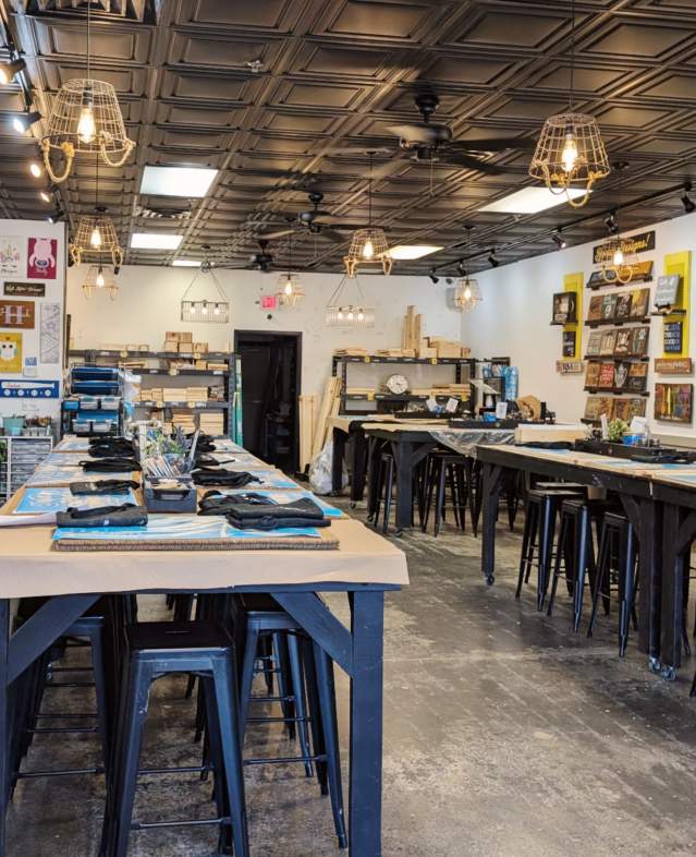 Inside the Board & Brush Woodbury Studio featuring long tables, stools and artwork.