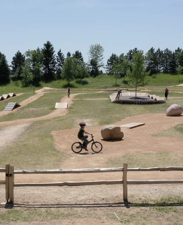 Carver Lake Bike Park outdoor trail showing bikers maneuvering different skill challenges.