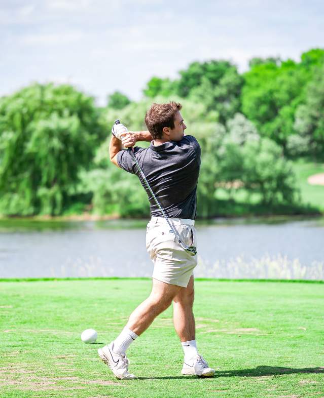 Golfer teeing off at Eagle Valley Golf Course with water feature in the background
