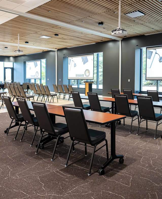 Meeting space shown with tables and chairs in Woodlands Room meeting space at Woodbury Central Park.