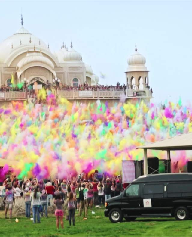Large group of people throwing colorful chalk at the Krishna Temple in Spanish Fork for the Holi Festival of Colors