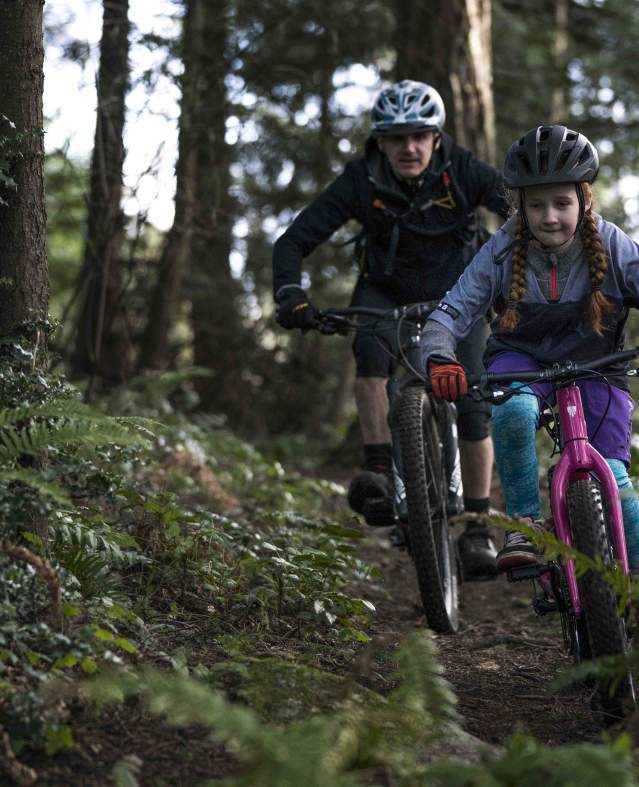Father and daughter mountain biking in the woods
