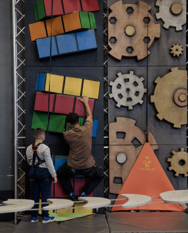 A boy gets ready to climb a colorful wall at Factoria.
