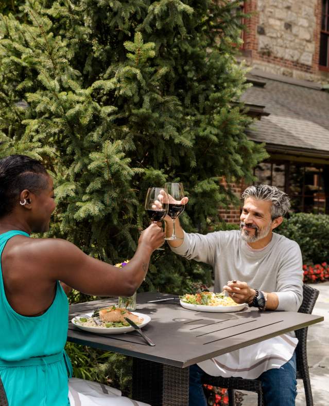 Two people toast one another with glasses of red wine.